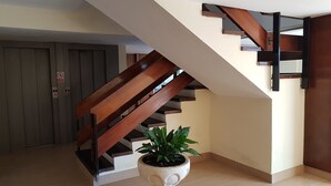 A staircase with wooden handrails and a potted plant at the bottom. - APARTMENT NEXT TO THE SEA WITH COMMUNITY GARDEN AND PLAZA PARKING WITH FREE WIFI (Platja d'Aro)