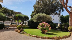 A well-maintained garden with a variety of trees and a central flower bed. - APARTMENT NEXT TO THE SEA WITH COMMUNITY GARDEN AND PLAZA PARKING WITH FREE WIFI (Platja d'Aro)