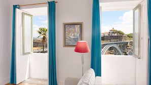 Habitación con vista a un puente y palmeras, un cuadro enmarcado y una lámpara.