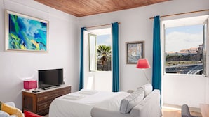 Habitación de hotel con cama, televisión, escritorio y vistas a un puente y edificios.