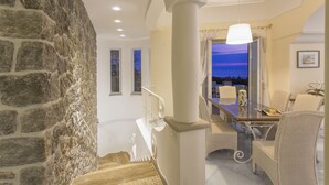 A dining area with a table and chairs, a stone wall, and a view of the sky. - Luxury villa with panoramic swimming pool in Ischia, near Amalfi Coast (Forio)