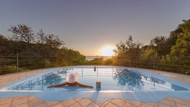 A swimming pool with a tiled deck, surrounded by a metal fence and trees. - Luxury villa with panoramic swimming pool in Ischia, near Amalfi Coast (Forio)