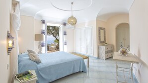 A bedroom with a bed, bedside table, lamp, wardrobe, and a view of the sea. - Luxury villa with panoramic swimming pool in Ischia, near Amalfi Coast (Forio)