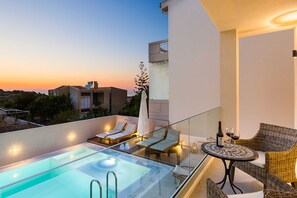 A rooftop pool area with lounge chairs and a table, overlooking a sunset. - Luxury Villa Amelia (Chania)