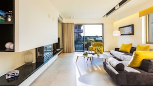 A modern living room with a sofa, coffee table, and a view of the outdoors. - Luxury Villa Amelia (Chania)