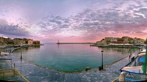 A waterfront promenade with buildings on both sides, a clear sky, and a calm sea. - Luxury Villa Amelia (Chania)