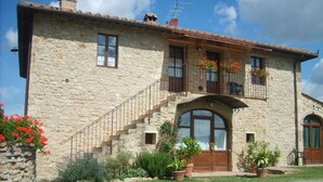 A stone building with a staircase, arched door, and potted plants. - CHARMING APARTMENT WITH POOL - 40 KM FLORENCE, 20 KM SIENA, 15 KM S. GIMIGNANO (Monteriggioni)