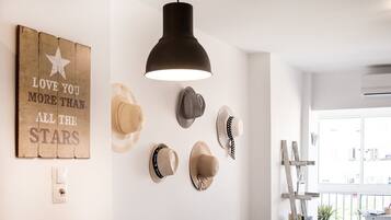 A room with a wooden wall decoration, a black pendant light, and several hats hanging on the wall.