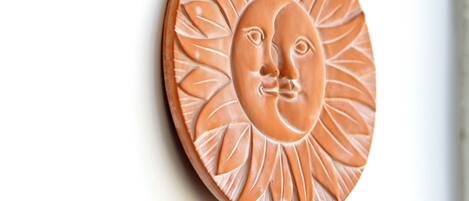 A ceramic wall decoration with a sun and face design.