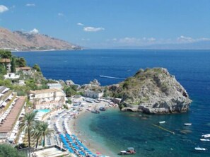 A coastal hotel with a beach, boats, and a rocky outcrop. - Holiday House Da Rosa (Letojanni)