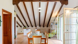 A dining area with a wooden table and chairs, a white vase, and a view of a kitchen and dining room through a glass door. - Ca du Pescou, Rapallo (Rapallo)