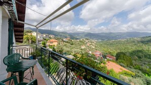 A balcony with a view of a hillside village, a green chair, and a table. - Ca du Pescou, Rapallo (Rapallo)