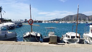 Un port de plaisance avec des bateaux amarrés, un ciel dégagé et un paysage vallonné en arrière-plan.