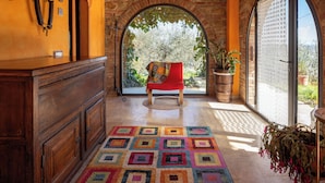 A cozy room with a wooden bench, a colorful rug, and a view of greenery through an arched window. - Il Poggio dell'Eremita (Sinalunga)