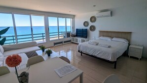A bedroom with a bed, bedside tables, a TV, and a view of the sea. - LOFT PLAYA MUCHAVISTA (El Campello)