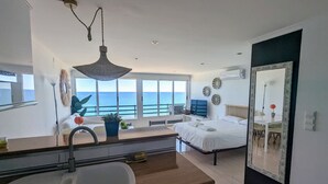 A modern hotel room with a large window, a bed, a desk, and a bathroom. - LOFT PLAYA MUCHAVISTA (El Campello)