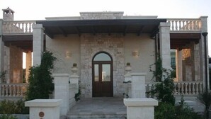 A stone building with a central arched doorway, flanked by two columns with circular designs.