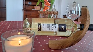 A bottle of Castello del Monte Progetto Proteina wine, a candle, and a glass of wine on a table with a red tablecloth.