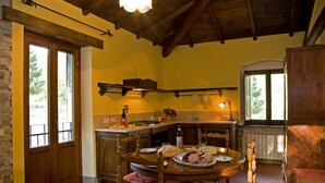 A rustic kitchen with a wooden table set for dining, a stone wall, and a window overlooking greenery. - CASETTA green park, equipped, near center village OPTIONAL HOT TUB exclusive use (Pratovecchio)