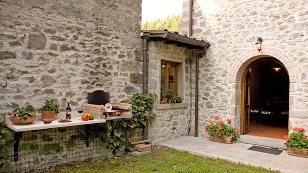 A stone building with a small outdoor seating area, a fire pit, and potted plants. - CASETTA green park, equipped, near center village OPTIONAL HOT TUB exclusive use (Pratovecchio)