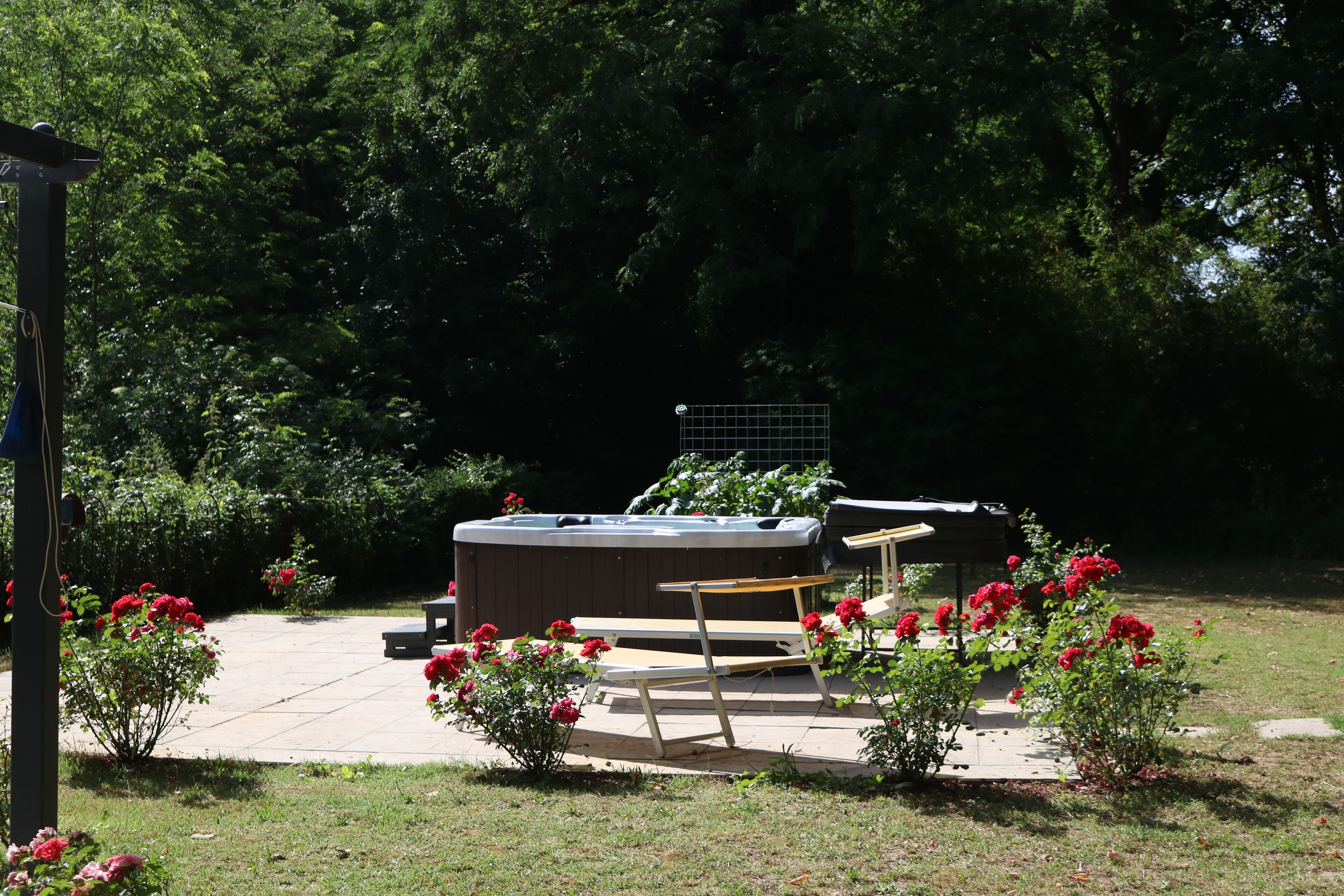 A hot tub surrounded by a patio area with a wooden bench and a grill.