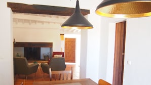 A dining area with a wooden table, chairs, and a hanging light fixture.