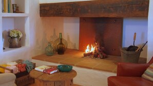 A cozy living room with a fireplace, a wooden coffee table, and a red armchair.