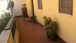 A balcony with terracotta tiles, potted plants, and a wooden cabinet. - Holiday Apartment Da Rosa Studio (Letojanni)