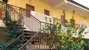 A multi-story building with a staircase, a balcony, and a window with shutters. - Holiday Apartment Da Rosa Studio (Letojanni)