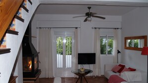 Een woonkamer met een open haard, een televisie, een bank, een tafel en een plafondventilator.
