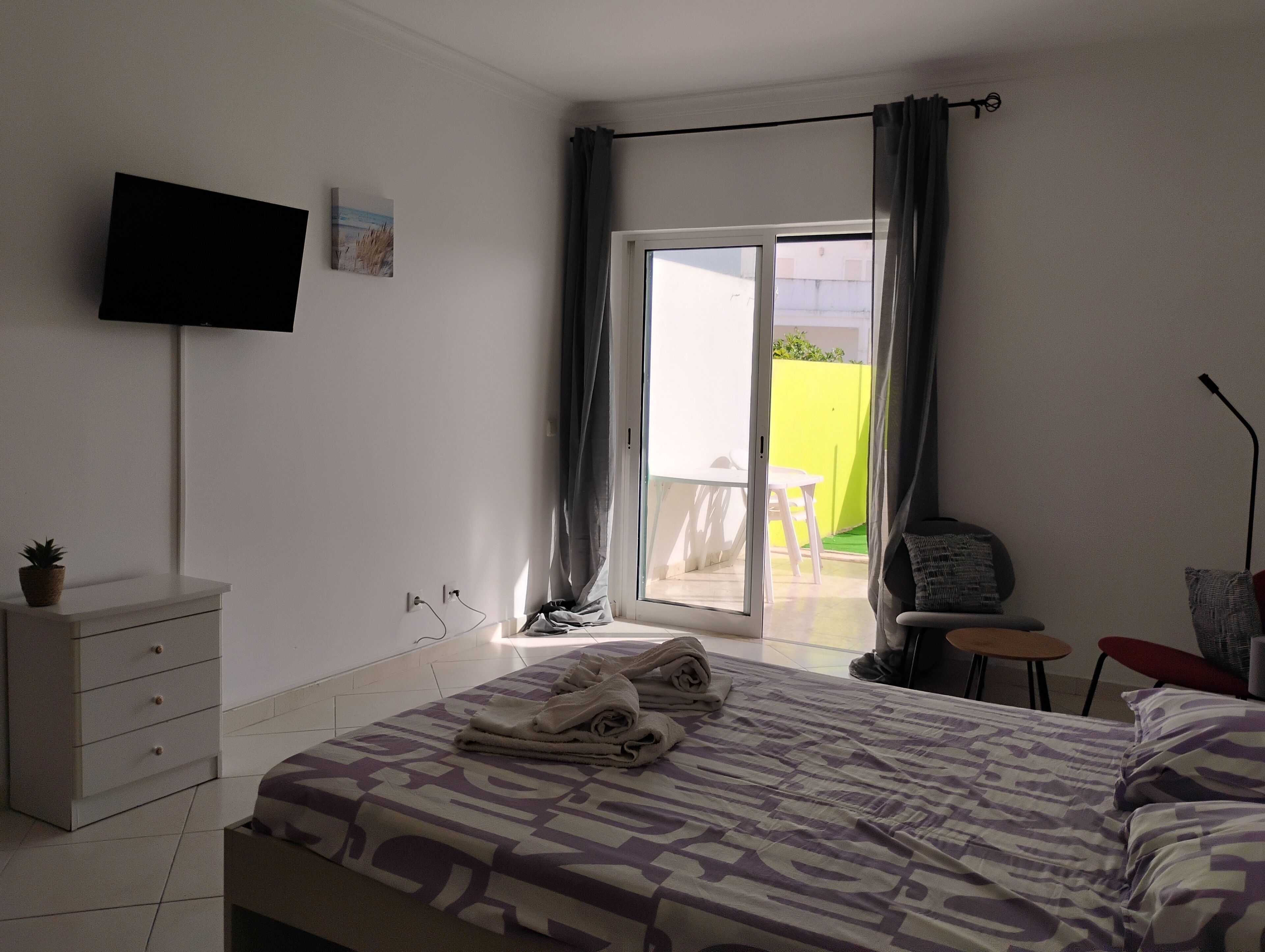 A bedroom with a bed, a TV, a desk, and a chair.