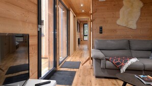 Un interno moderno con pavimento in legno, un divano grigio, un tavolo bianco e un telecomando sul tavolo.