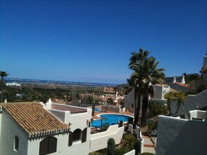 A pool area with a view of the sea, surrounded by white buildings with terracotta roofs and palm trees. - 2 Bed Det.Villa in La Manga Club.  5g Wi-Fi, Pool, A/C  winter monthly discounts (Los Belones)