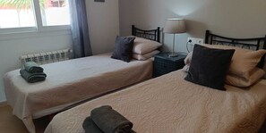 Une chambre d’hôtel avec deux lits, un radiateur, une lampe et une fenêtre avec des rideaux.