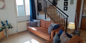 Un salon avec un canapé en cuir marron, une lampe et un escalier.