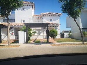 Un bâtiment blanc avec un toit en tuiles, une entrée abritée et un petit jardin.