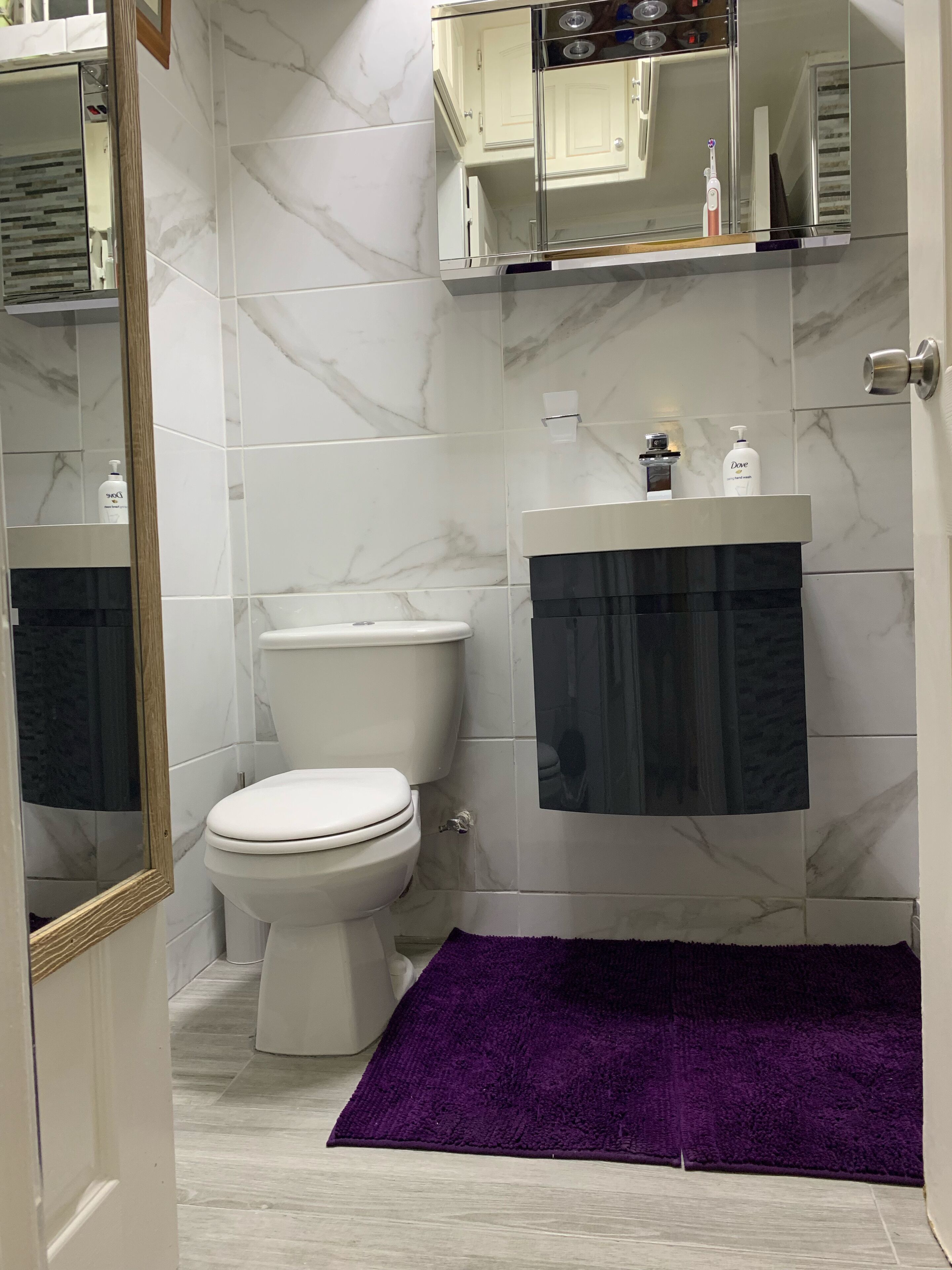 A bathroom with a toilet, a sink, and a mirror.