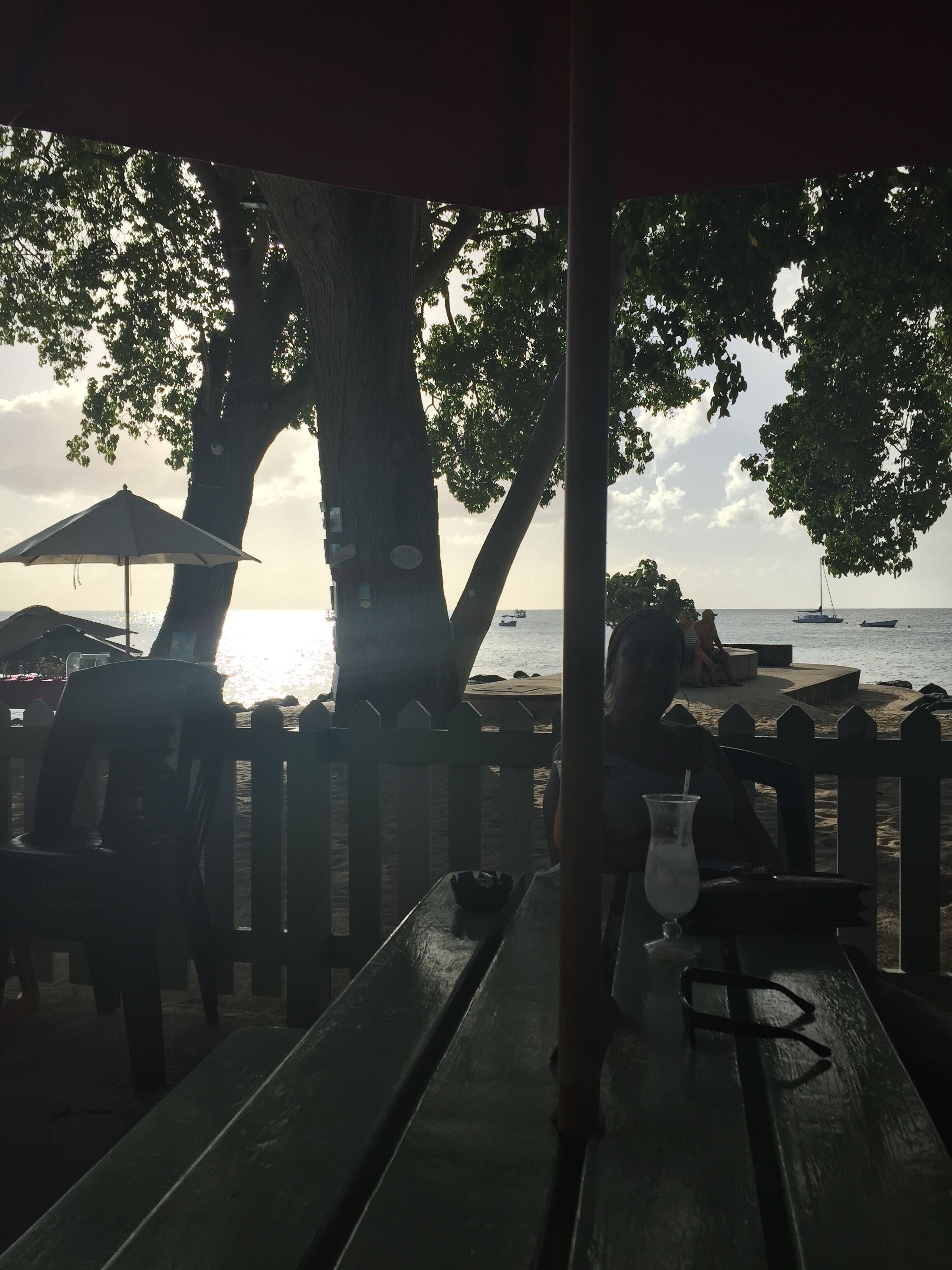 A beachside café with wooden tables and benches, overlooking the sea.
