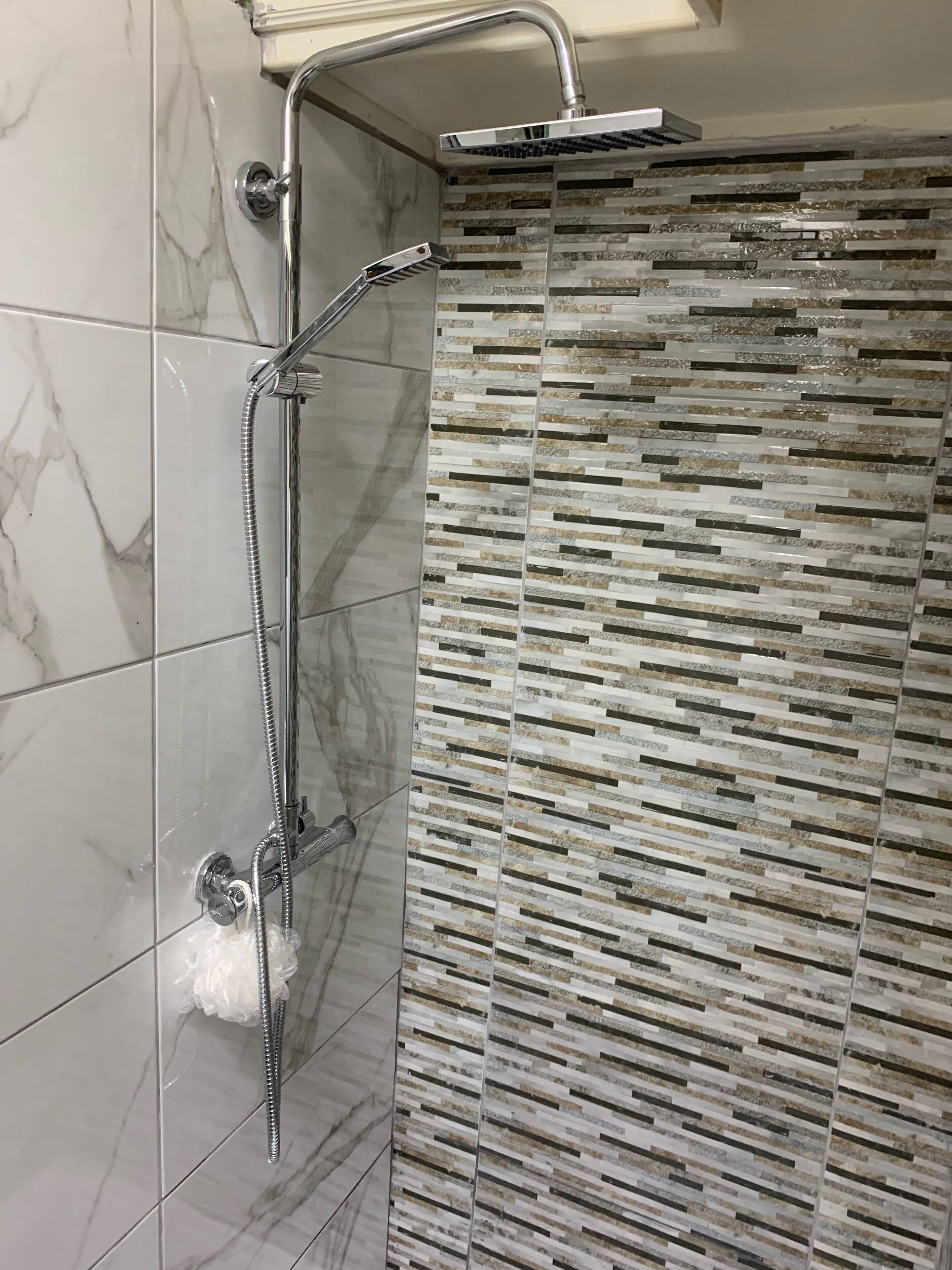 A shower with a modern design, featuring a glass enclosure and a tiled wall with a geometric pattern.
