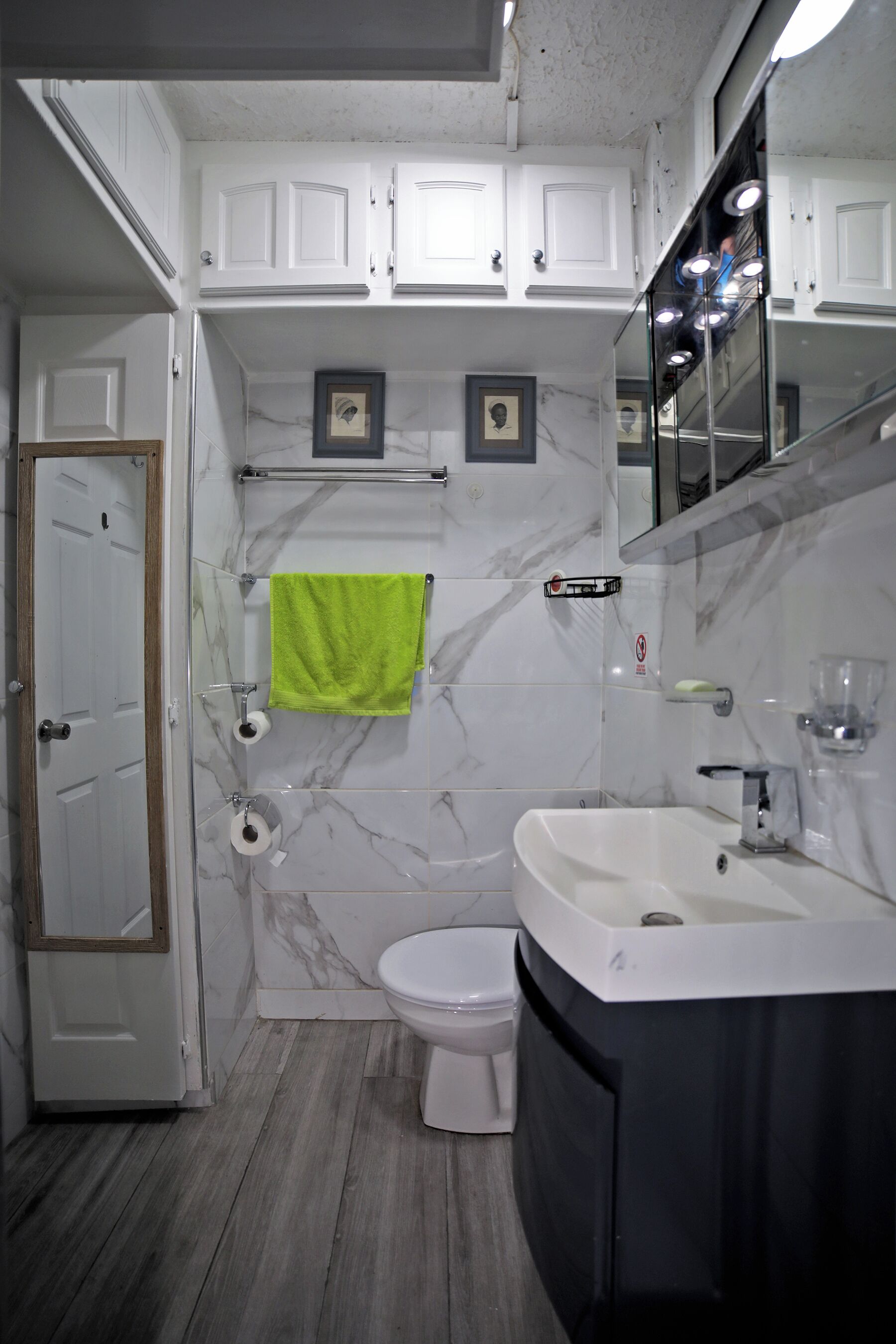 Ein Badezimmer mit Toilette, Waschbecken mit Spiegel und Duschbereich.