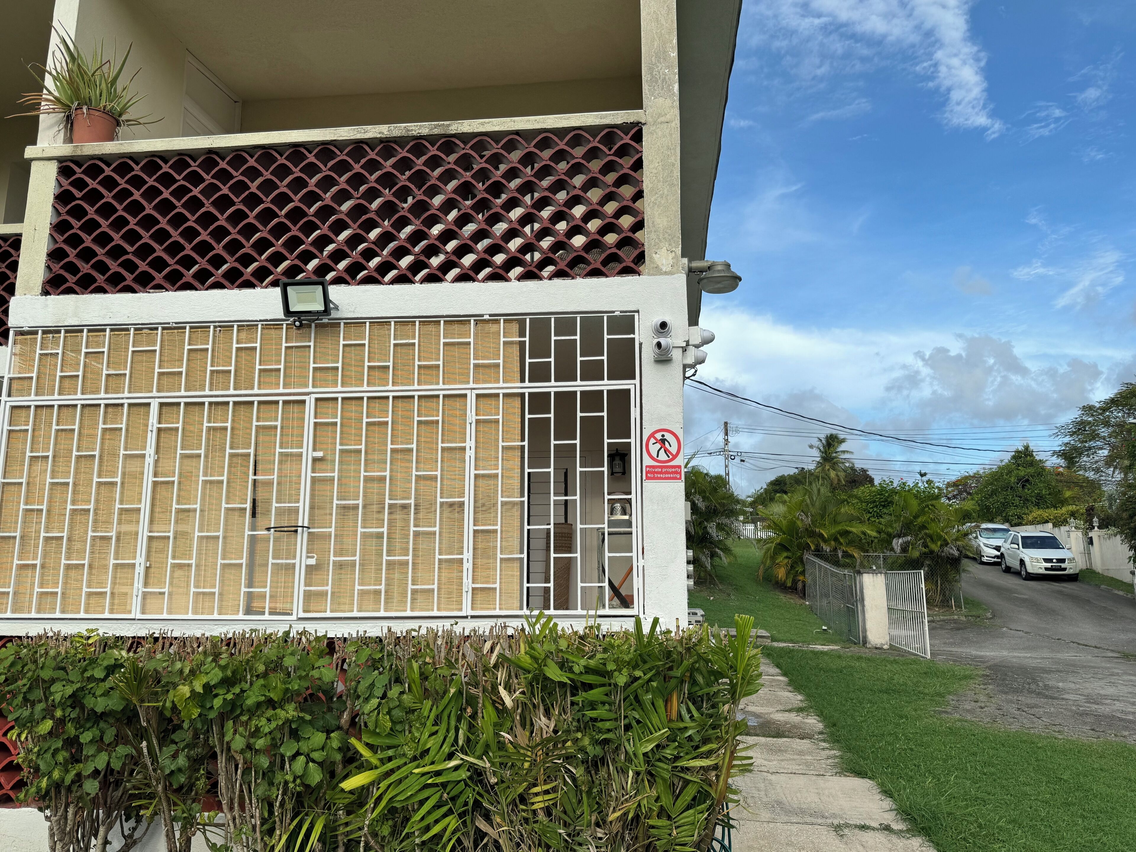 A residential building with a gated entrance, a security camera, and a 'No Trespassing' sign.