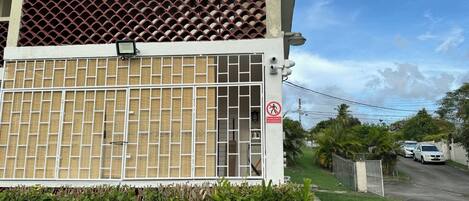 A residential building with a gated entrance, a security camera, and a 'No Trespassing' sign.