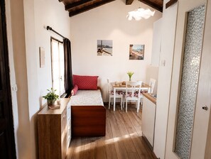 Une petite pièce agréable et confortable, avec un lit, un bureau et une chaise, un plancher en bois et une fenêtre avec des rideaux.