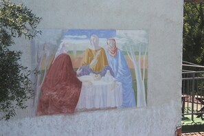 Une fresque représentant trois personnages assis autour d’une table.