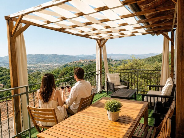 Un espace extérieur abrité, aménagé avec des sièges, et offrant une vue sur un paysage vallonné.