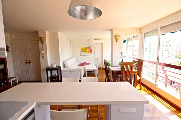 A modern apartment with a kitchen, dining area, and a balcony with a view of the city.