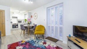 A modern living room with a yellow armchair, a TV, and a colorful rug. - Minster's Reach Holiday Apartment (YORK)