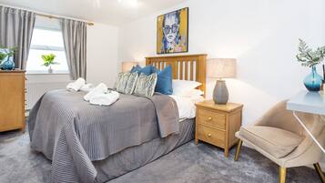 A modern bedroom with a bed, bedside tables, a chair, and a painting on the wall.