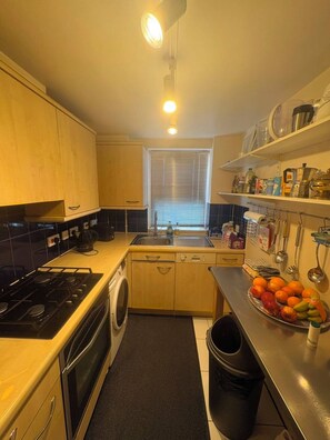 A compact kitchen with a stove, sink, and a small window.