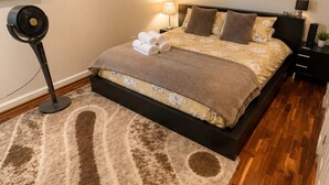 Un dormitorio con cama, ventilador, mesita de noche y lámpara de pared.